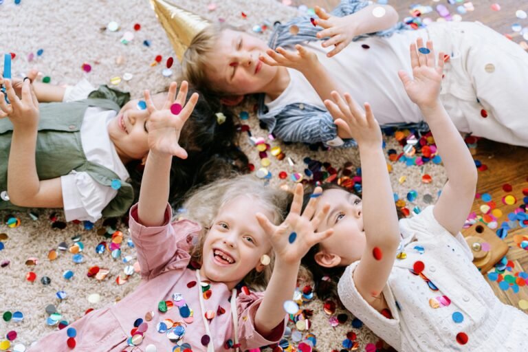 Joyful children having fun with colorful confetti indoors, enjoying a festive celebration.